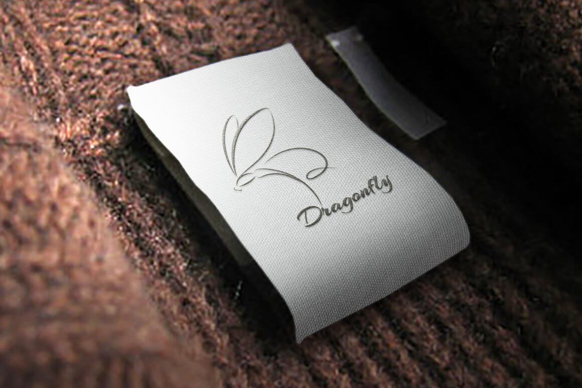 Gray dragonfly logo on brown woven fabric.