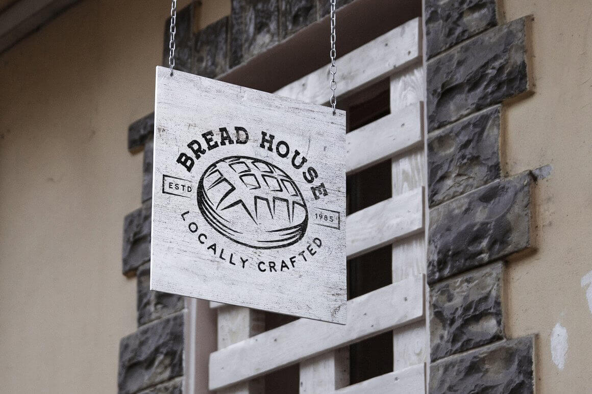 Black and white bakery sign "Bread House, locally crafted" on iron chains.