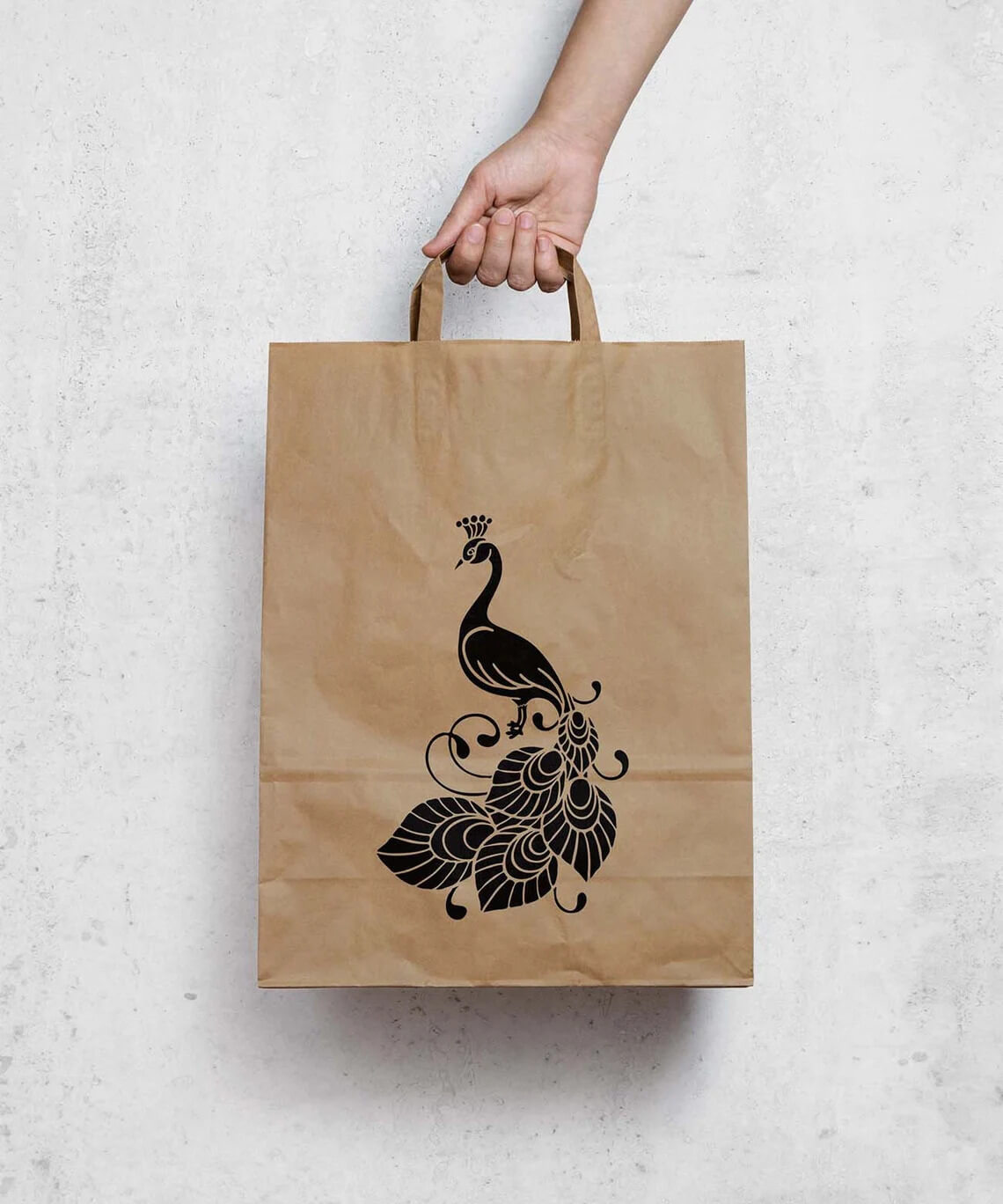 Person holding a brown paper bag with a peacock on it.