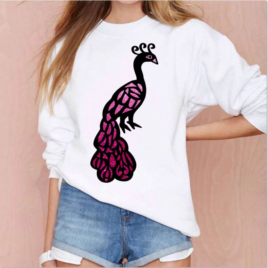 Woman wearing a white sweater with a pink and black bird on it.