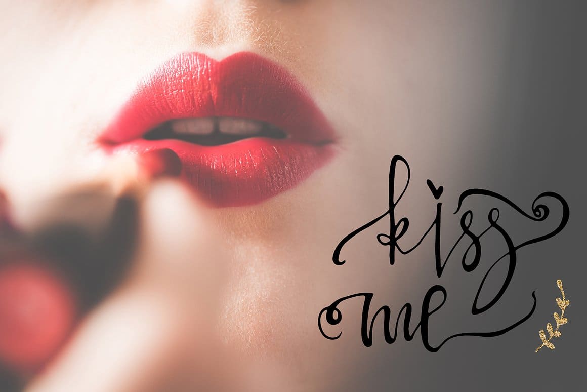 The girl paints her lips with red lipstick and the inscription "Kiss me" is next to it.