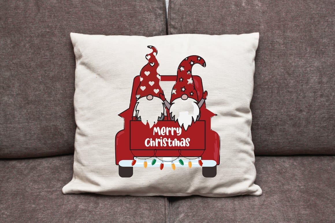 Image of a white pillow with gnomes in red Christmas clothes.