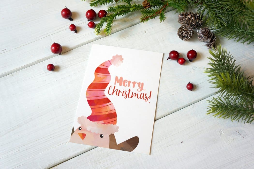 A card with the image of a Christmas penguin with a red hat on his head.