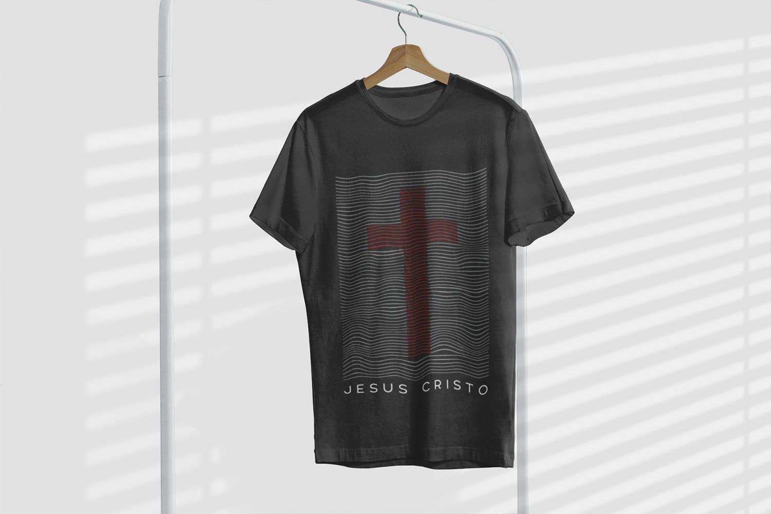 A black t-shirt with a print of Jesus Christ under a red cross hanging on a hanger.