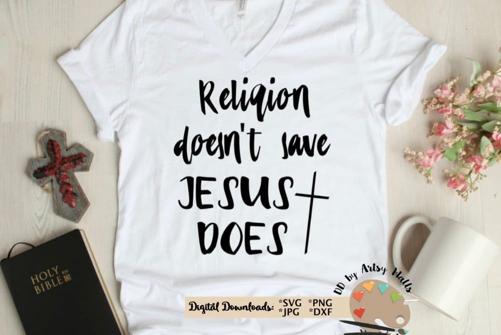 On a white T-shirt it is written "Religion doesn't save jesus does", and next to it lies a cross and a Bible.