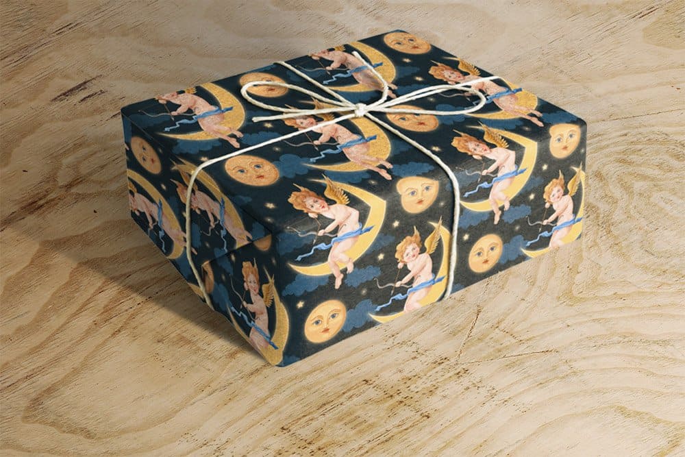 On a wooden table lies a gift decorated with dark blue wrapping paper with a bright mysterious design.
