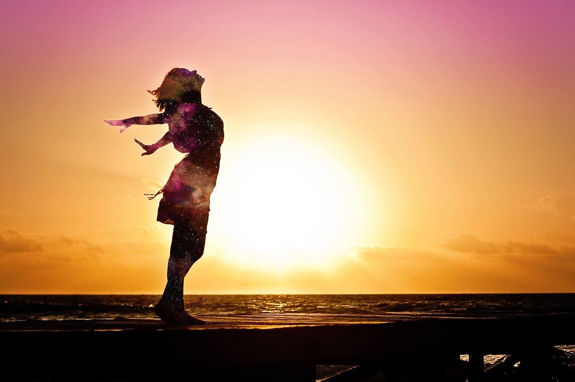 The girl is full of inspiration against the background of an amazing sky.