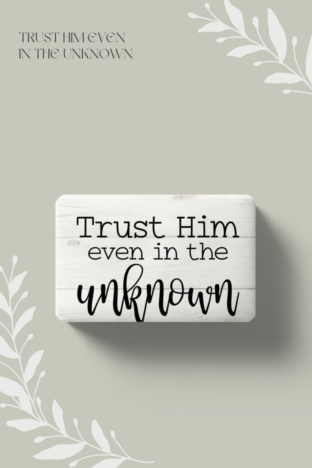 An inscription about trust in God is written on a white wooden object.