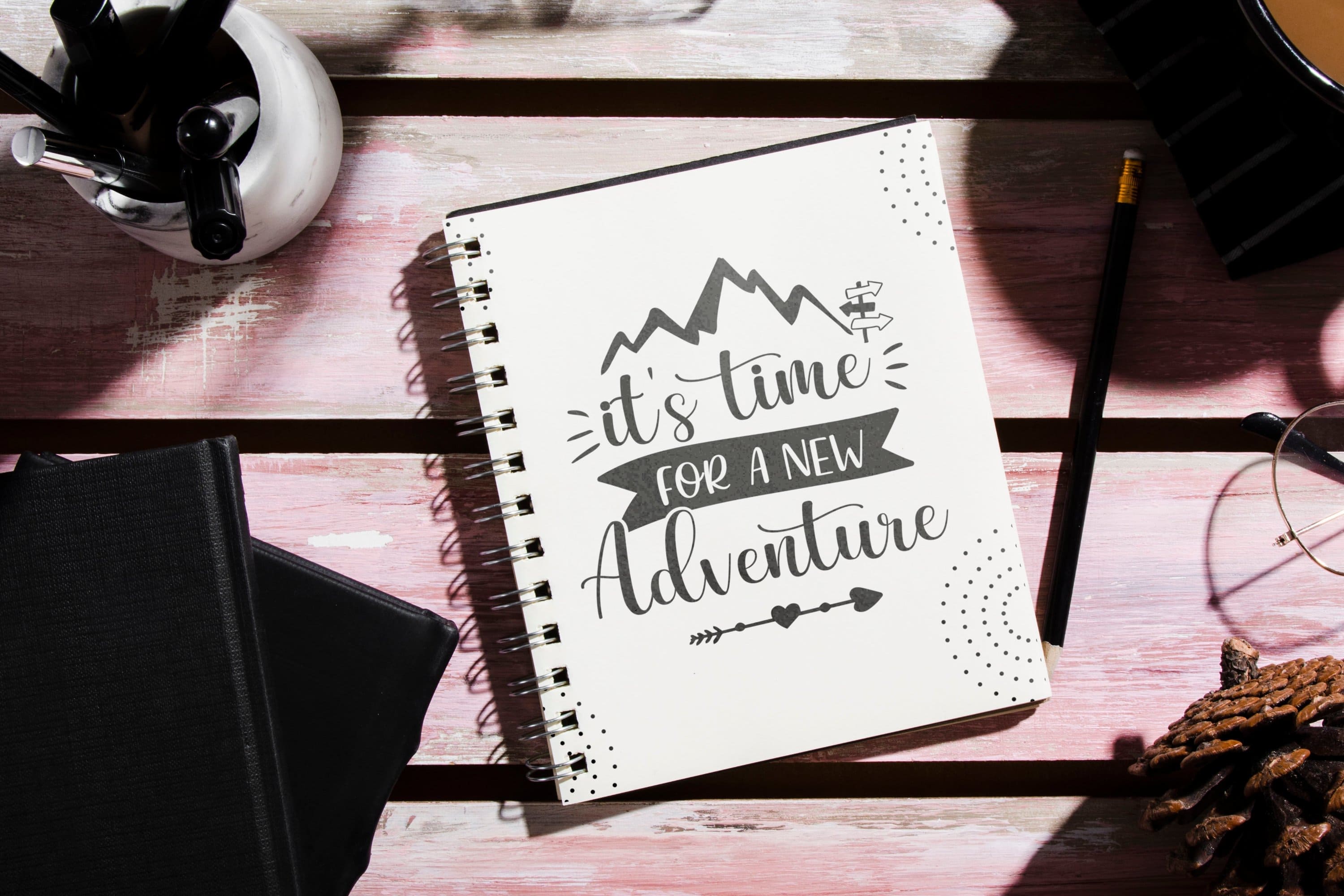 White notebook with "It's time for a new Adventure" black and white print.