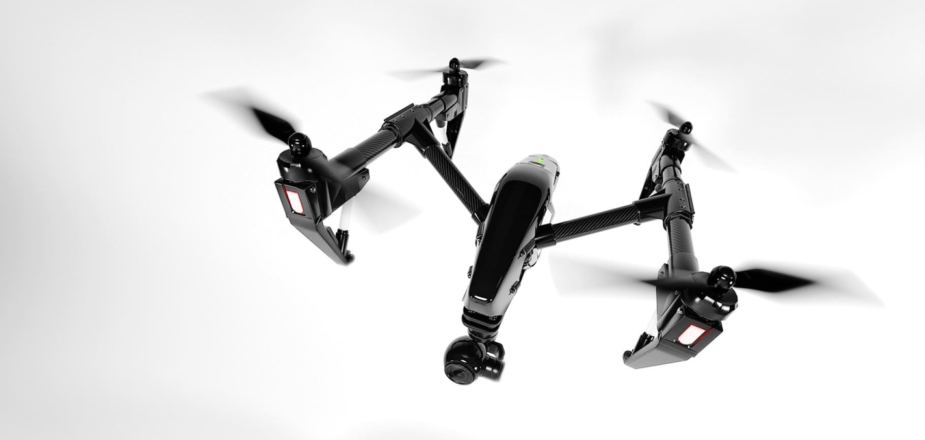 Black quadcopter flying in the air on a white background.