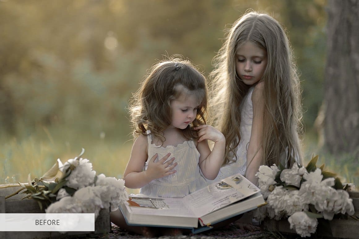 Gray image of two girls reading a book.