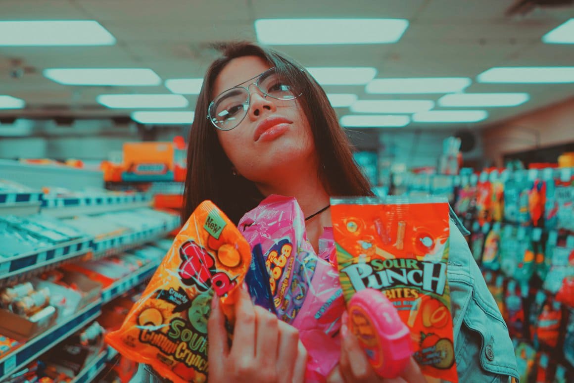 An image of a brunette girl in a store, who picked up goodies.