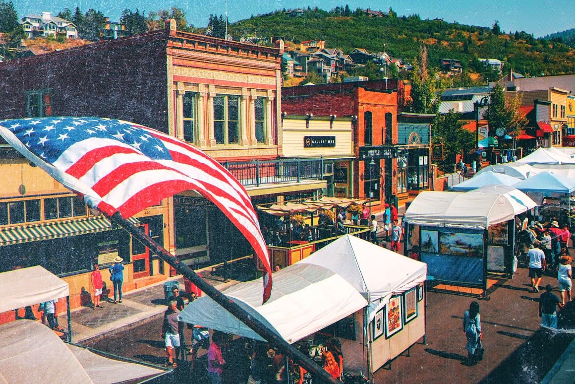 Photograph of buildings with tents and an American flag.