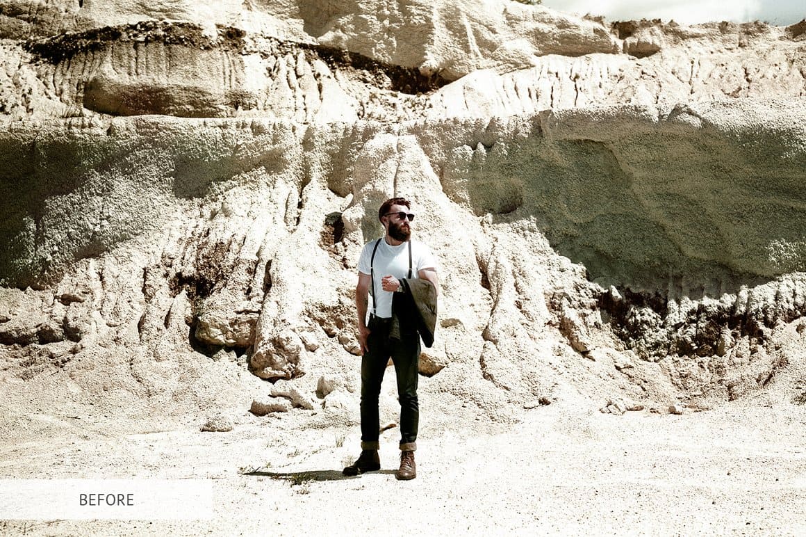 A guy in fashionable clothes stands among the sand mountains.
