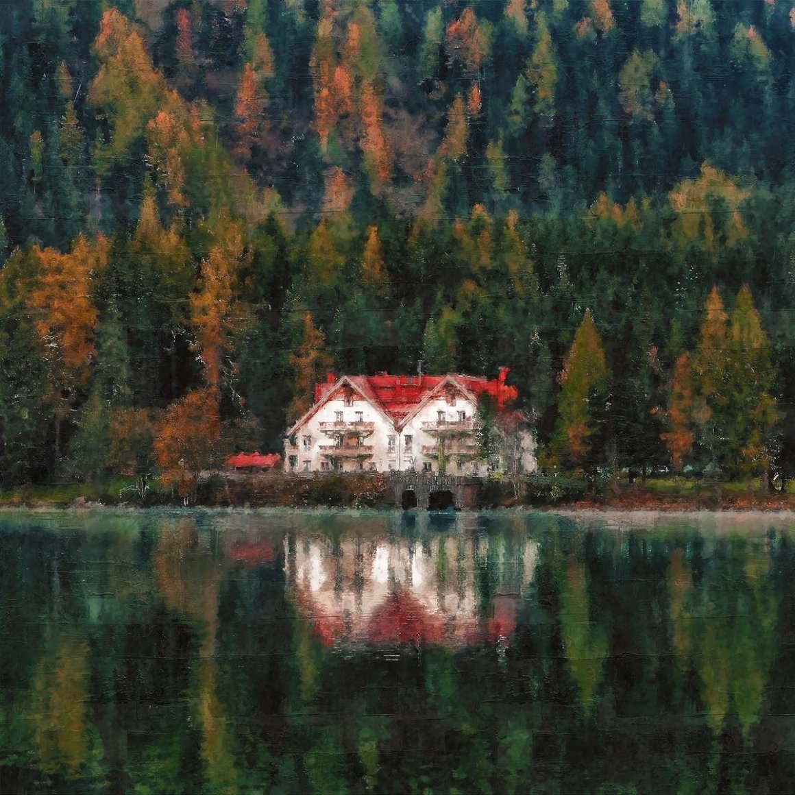 White and orange house beside forest and body of water.